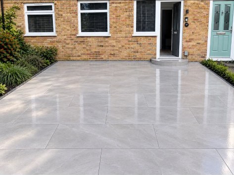 The same front after: large light-grey porcelain slabs and planted borders