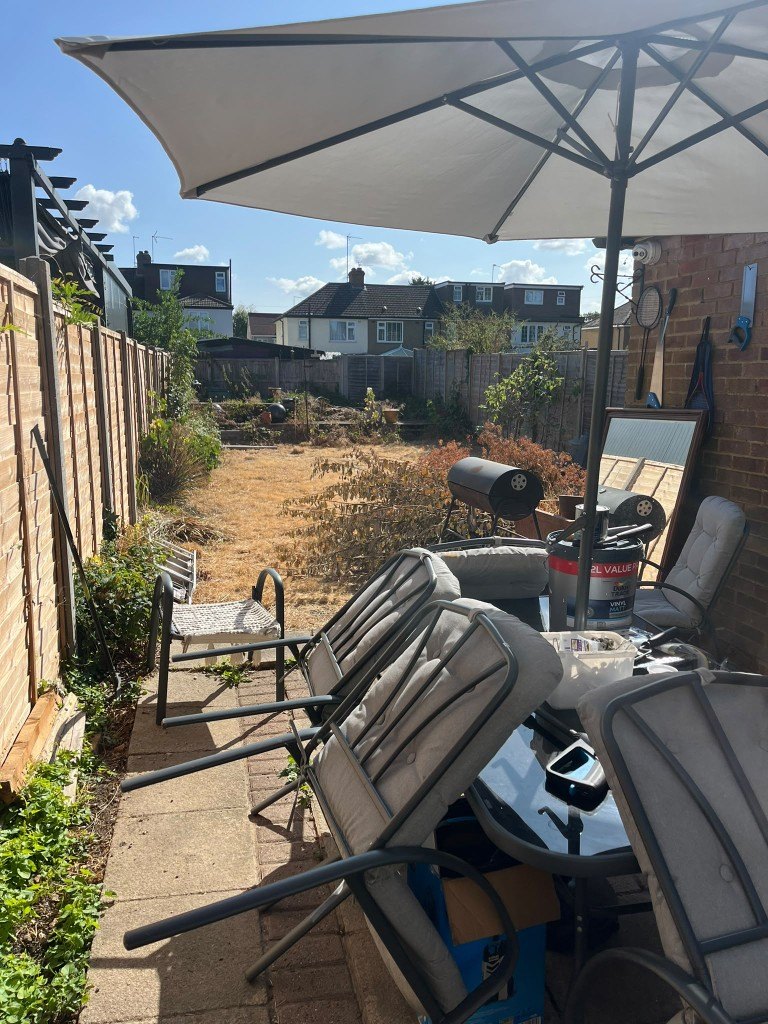 Garden before the work: dry lawn, overgrown beds and patio furniture