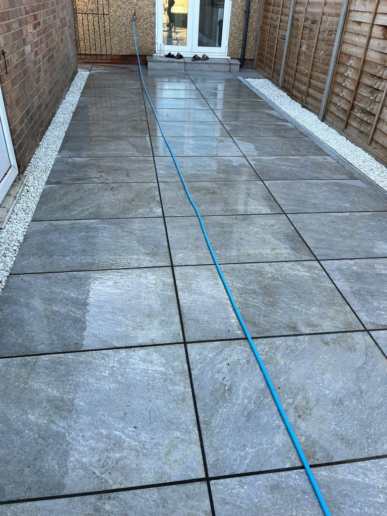 Finished side-return patio in large grey tiles with white gravel borders
